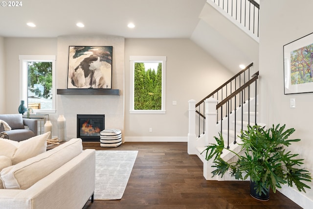 living area with a healthy amount of sunlight, a large fireplace, baseboards, and dark wood finished floors