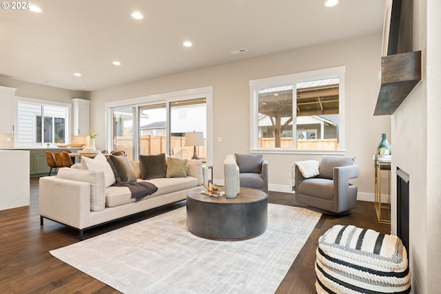 living room with baseboards, visible vents, dark wood-type flooring, a fireplace, and recessed lighting