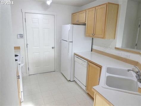 kitchen featuring sink, white dishwasher, light tile floors, and light brown cabinetry