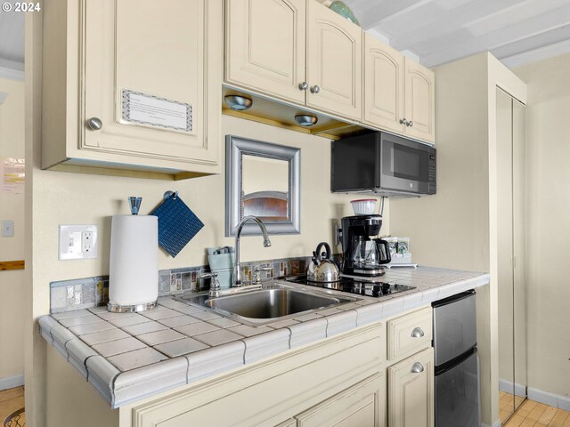 kitchen with cream cabinetry, sink, stainless steel appliances, and tile countertops