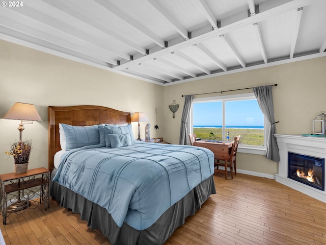 bedroom with beamed ceiling and light hardwood / wood-style flooring