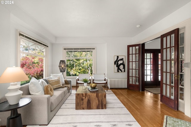 living room with french doors, radiator heating unit, and light wood-type flooring