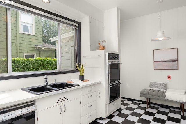 kitchen featuring white cabinetry, multiple ovens, dishwasher, sink, and decorative light fixtures