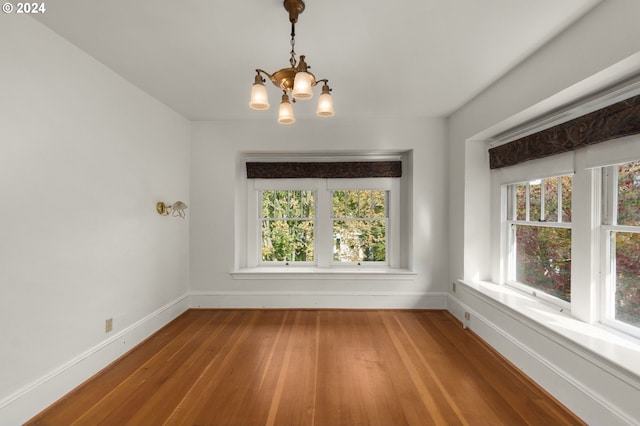 unfurnished dining area with a chandelier, wood-type flooring, and a wealth of natural light