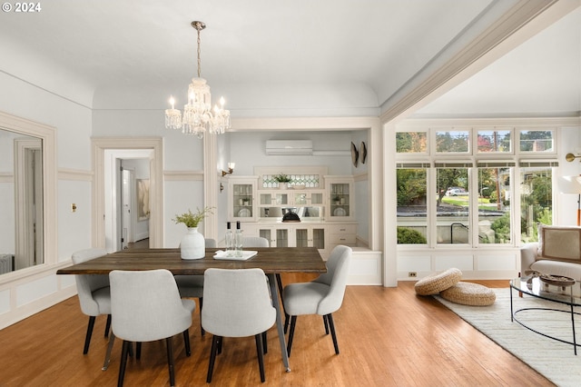 dining space featuring an inviting chandelier, a wall mounted AC, and light wood-type flooring