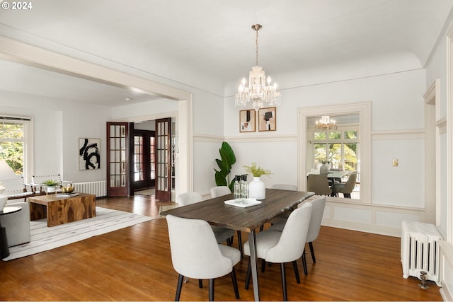 dining space featuring radiator, french doors, an inviting chandelier, and dark hardwood / wood-style floors