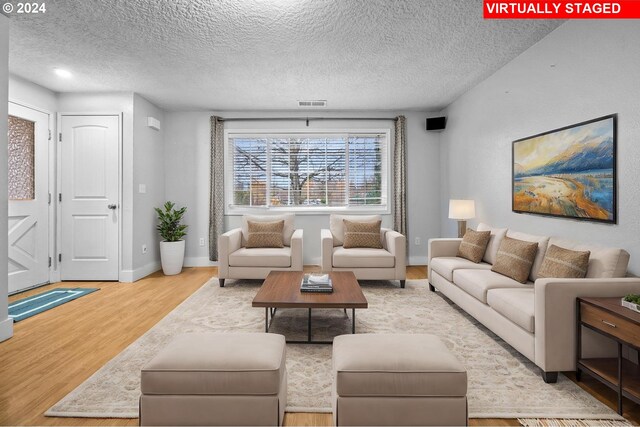 living room featuring light hardwood / wood-style flooring and a textured ceiling