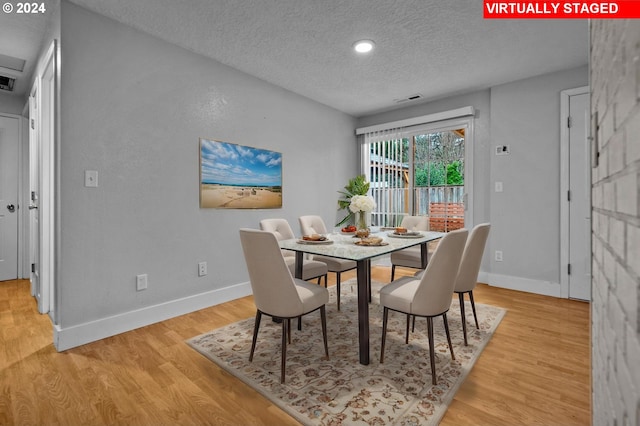 dining area with a textured ceiling and light hardwood / wood-style floors