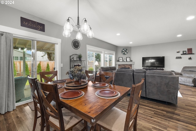 dining area featuring a stone fireplace, plenty of natural light, dark hardwood / wood-style floors, and a notable chandelier