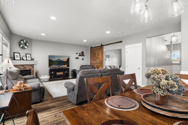 dining room featuring a barn door, hardwood / wood-style floors, and a fireplace