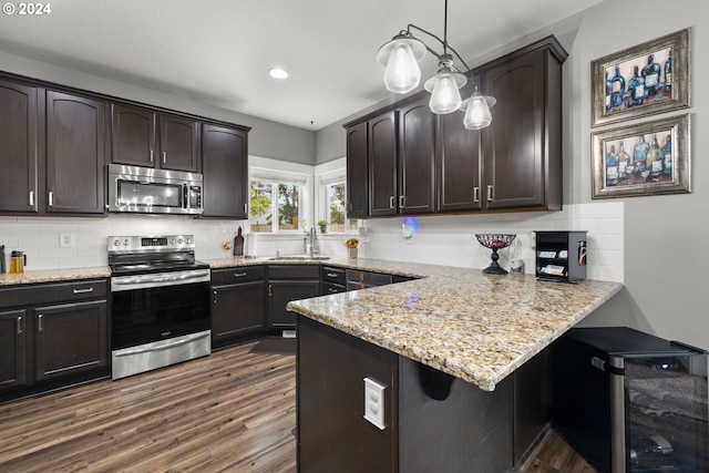 kitchen featuring dark brown cabinetry, sink, hanging light fixtures, tasteful backsplash, and appliances with stainless steel finishes