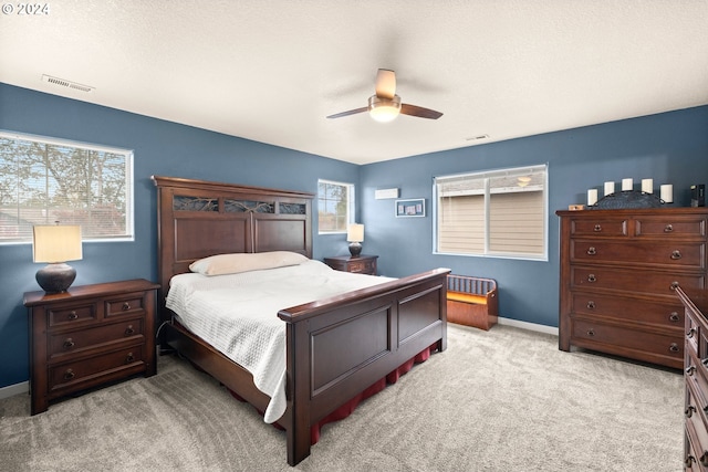 carpeted bedroom featuring multiple windows and ceiling fan