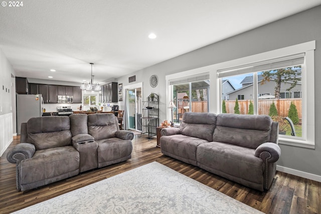 living room featuring dark hardwood / wood-style floors, a healthy amount of sunlight, and an inviting chandelier