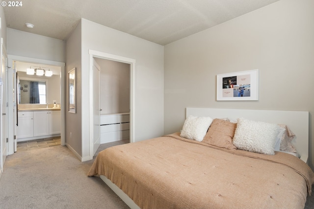 carpeted bedroom featuring ensuite bathroom and sink