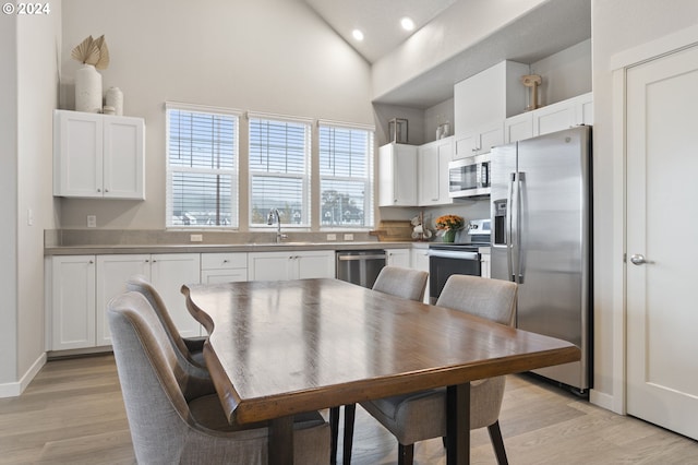 dining area with sink, high vaulted ceiling, and light hardwood / wood-style floors