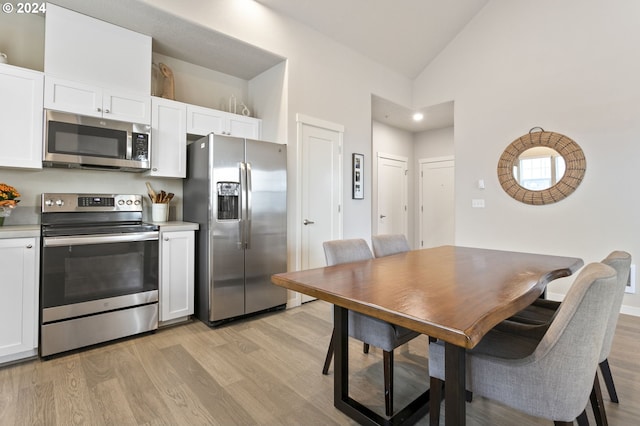 kitchen featuring light hardwood / wood-style floors, white cabinetry, stainless steel appliances, and high vaulted ceiling