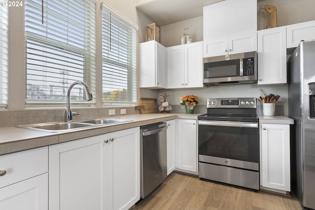 kitchen featuring stainless steel appliances, white cabinetry, plenty of natural light, and sink