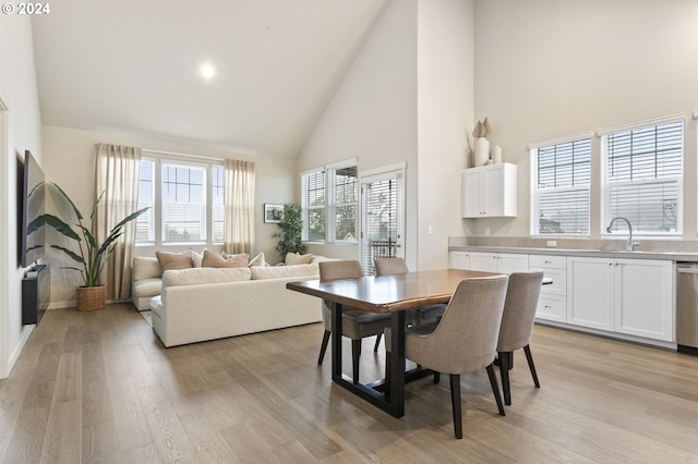 dining area with sink, high vaulted ceiling, and light hardwood / wood-style flooring