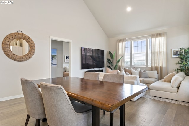 dining area with light wood-type flooring and high vaulted ceiling