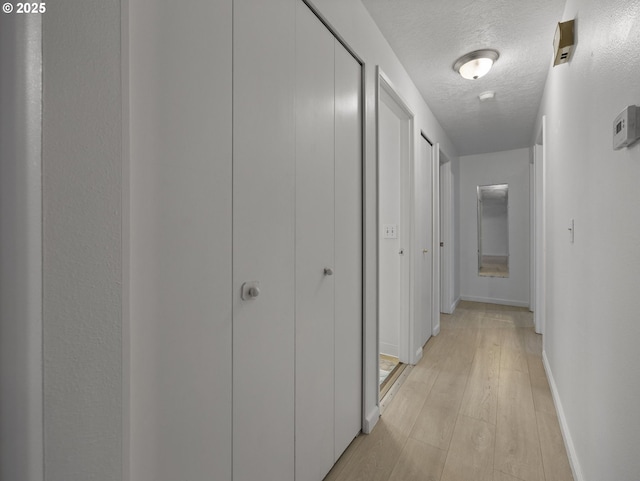 hall featuring light hardwood / wood-style floors and a textured ceiling