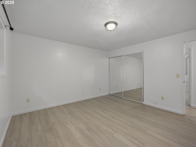 unfurnished bedroom with a textured ceiling, light hardwood / wood-style flooring, and a closet