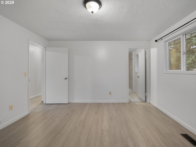 unfurnished room with light hardwood / wood-style floors and a textured ceiling