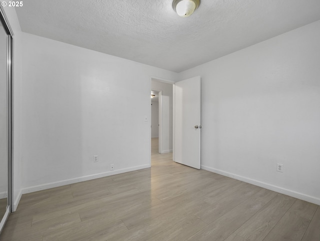 unfurnished room with a textured ceiling and light hardwood / wood-style floors