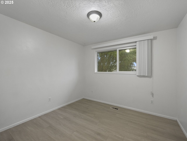 spare room with a textured ceiling and light wood-type flooring