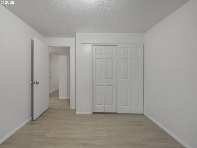 unfurnished bedroom featuring light wood-type flooring, a textured ceiling, and a closet