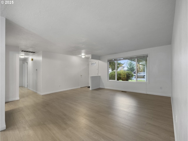 unfurnished living room featuring a textured ceiling and light hardwood / wood-style flooring