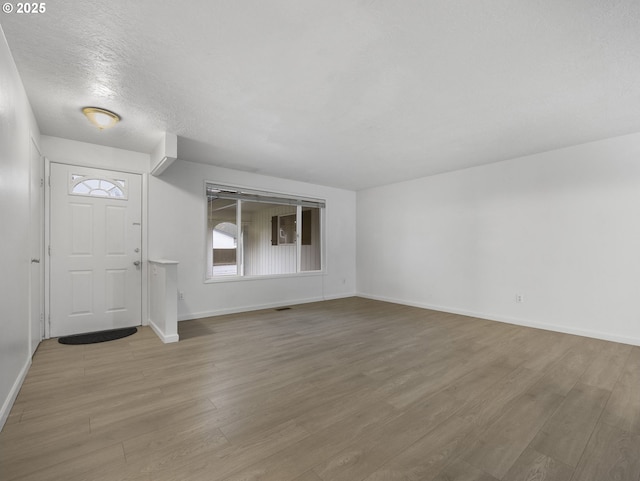 entryway with light hardwood / wood-style flooring and a textured ceiling