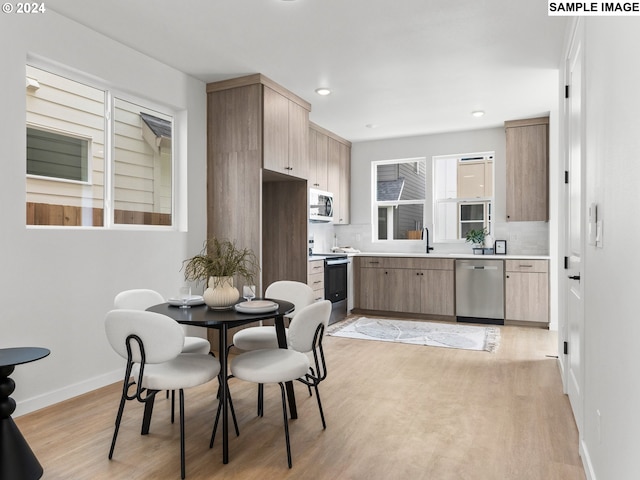 kitchen with appliances with stainless steel finishes, light hardwood / wood-style floors, backsplash, light brown cabinets, and sink