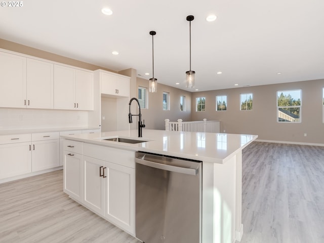 kitchen with dishwasher, white cabinetry, a kitchen island with sink, and sink