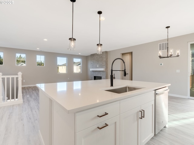 kitchen featuring a kitchen island with sink, dishwasher, hanging light fixtures, and sink