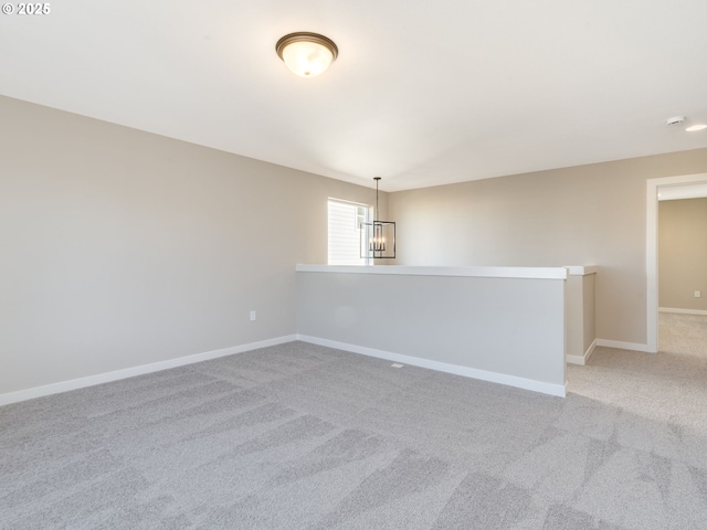 empty room with light colored carpet and an inviting chandelier