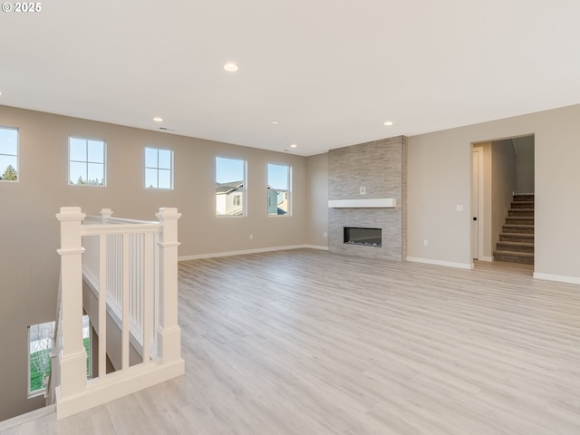 unfurnished living room featuring a fireplace, light hardwood / wood-style floors, and a wealth of natural light