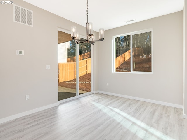 unfurnished dining area with wood-type flooring and a notable chandelier