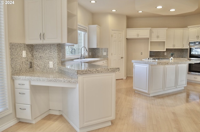 kitchen featuring sink, light stone countertops, light wood-type flooring, white cabinetry, and stainless steel appliances