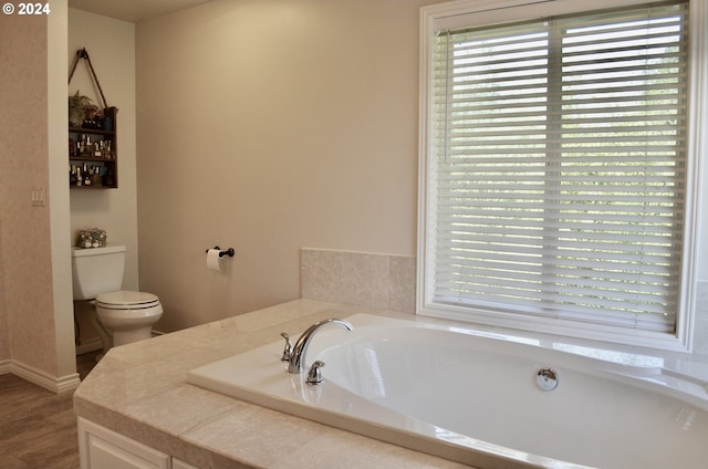 bathroom with a tub to relax in, wood-type flooring, a healthy amount of sunlight, and toilet