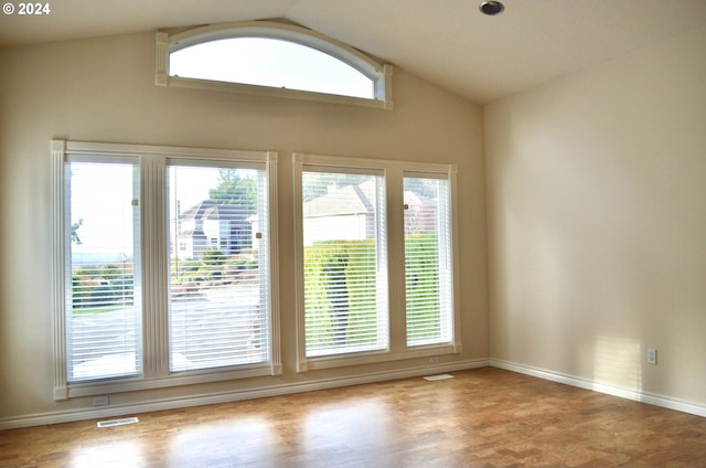 spare room with hardwood / wood-style floors and vaulted ceiling