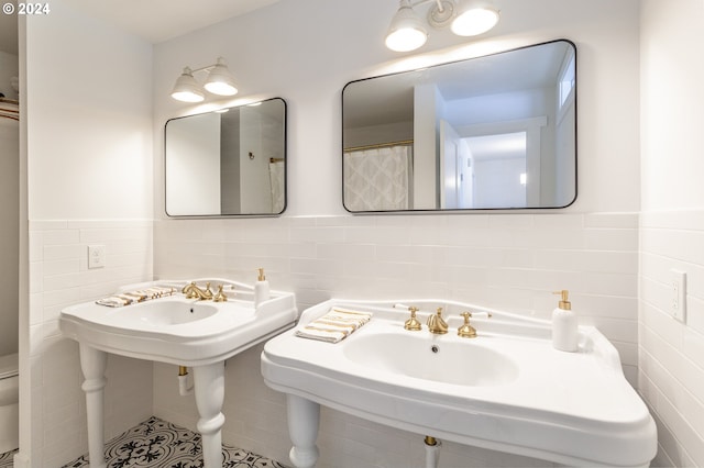 bathroom featuring tile patterned floors, double sink, tile walls, and toilet