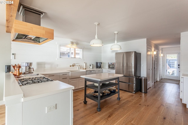 kitchen with appliances with stainless steel finishes, sink, decorative light fixtures, light hardwood / wood-style floors, and white cabinetry