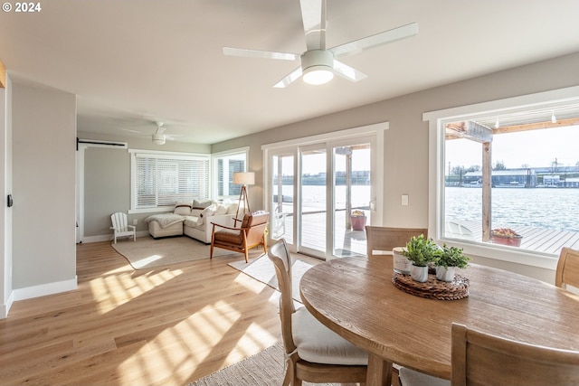 dining space with a water view, ceiling fan, and light hardwood / wood-style floors