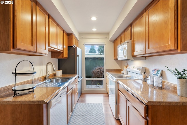 kitchen featuring white appliances, light hardwood / wood-style flooring, and sink