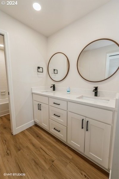 bathroom with hardwood / wood-style flooring and dual vanity