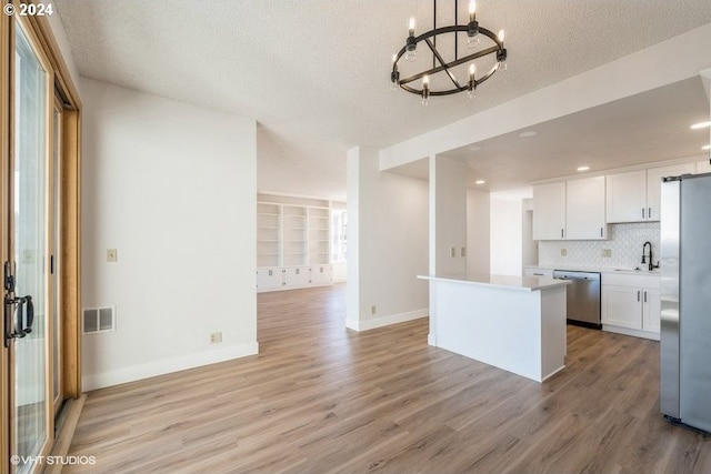 kitchen featuring appliances with stainless steel finishes, a notable chandelier, light wood-type flooring, and white cabinetry