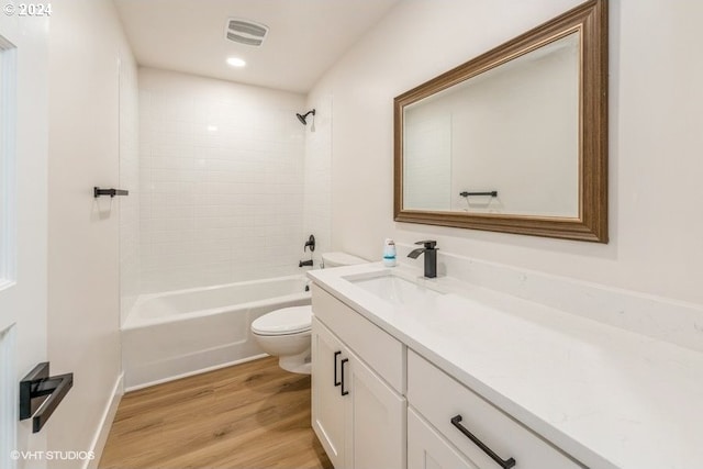 full bathroom featuring tiled shower / bath, vanity, hardwood / wood-style flooring, and toilet