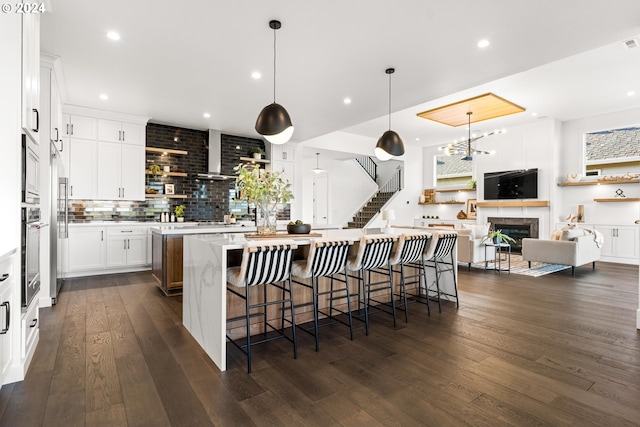 kitchen featuring a large island with sink, a breakfast bar area, tasteful backsplash, and dark hardwood / wood-style floors