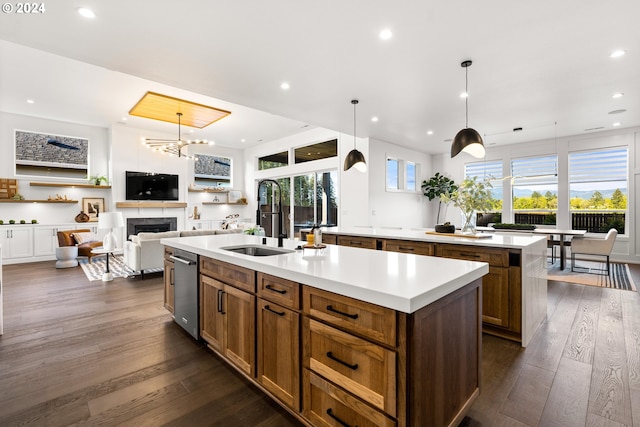 kitchen with hanging light fixtures, plenty of natural light, a center island with sink, and dark wood-type flooring