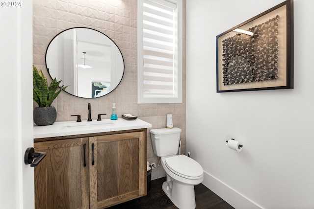 bathroom with wood-type flooring, tile walls, toilet, and vanity